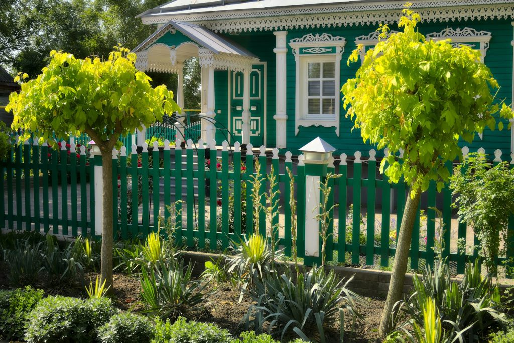 A green house with a picket fence.